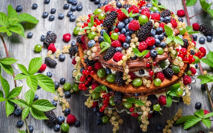 Berry cake with chocolate frosting on a wooden surface
