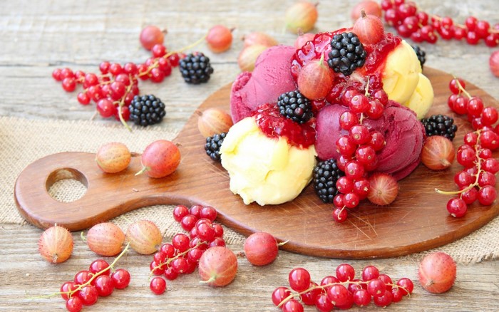 Ice cream with berries and fruit on a wooden board
