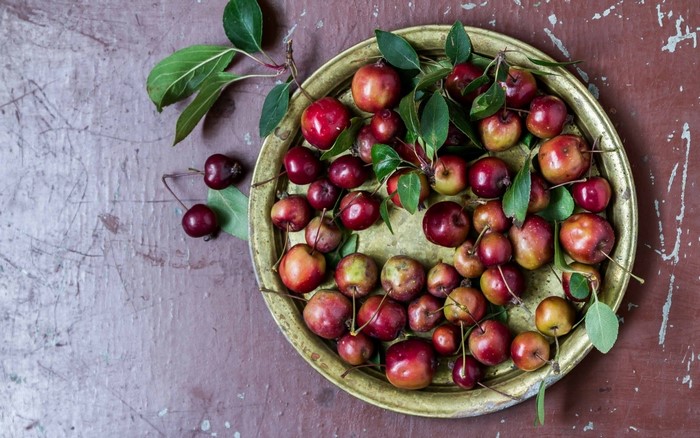 Crabapples and cherries on a brass plate