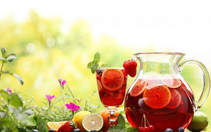 Pitcher and glass of fruit punch with fruits and flowers