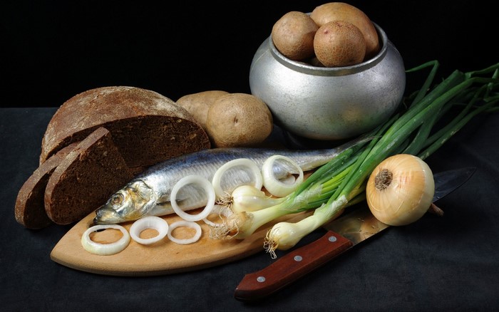 Still life of fish, bread, potatoes, and onions