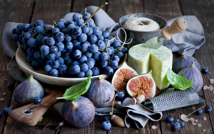 Grapes, figs, cheese, and blueberries on a wooden table