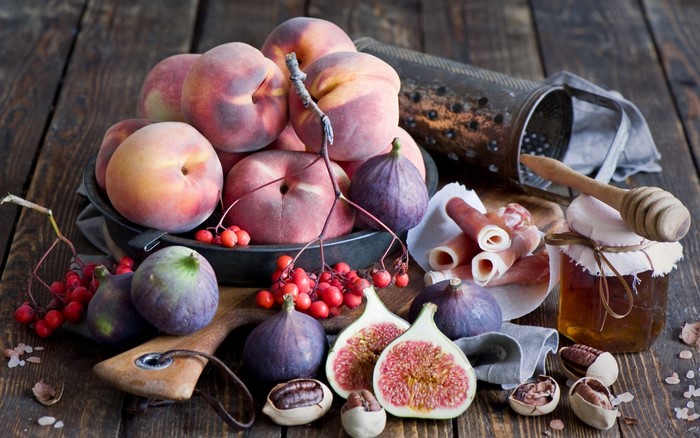 Still life of fruits, cured meat, and honey