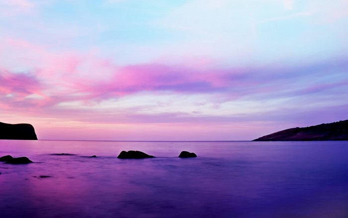 Purple sunset over the sea with rocky shore