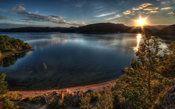 Sunset over a calm lake with forested hills