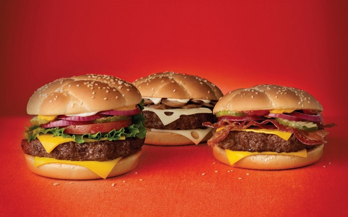 Three gourmet burgers on an orange surface