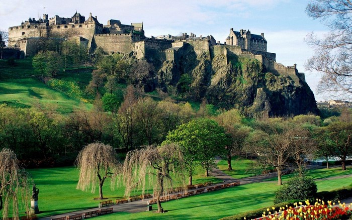 Edinburgh Castle on a rocky hill with a park in the foreground