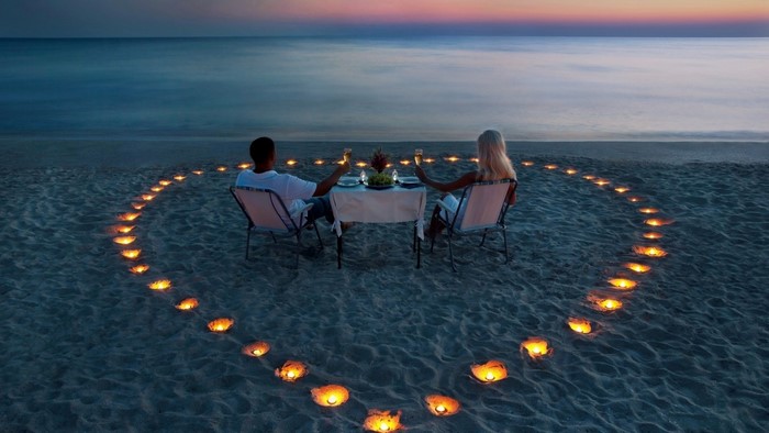 Couple having a romantic dinner on the beach at sunset