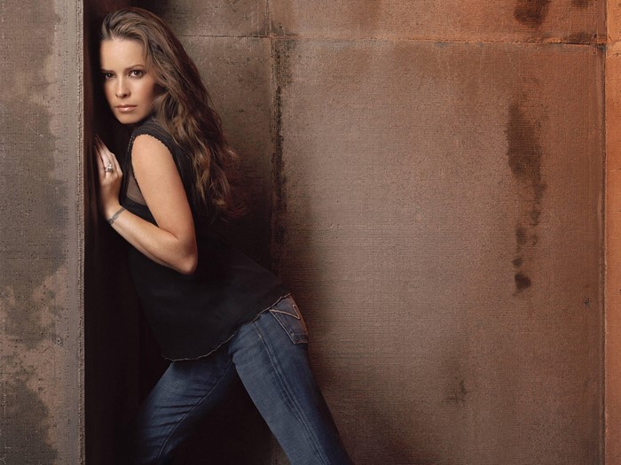 Holly Marie Combs leaning against a concrete wall