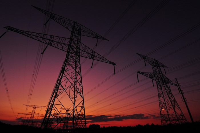 Transmission towers and power lines at sunset