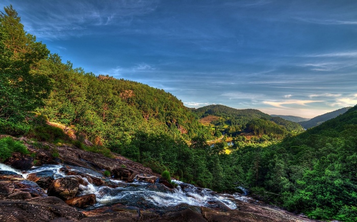 Waterfall flowing over rocks in a green mountain valley