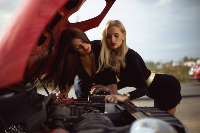Two women looking at a car engine