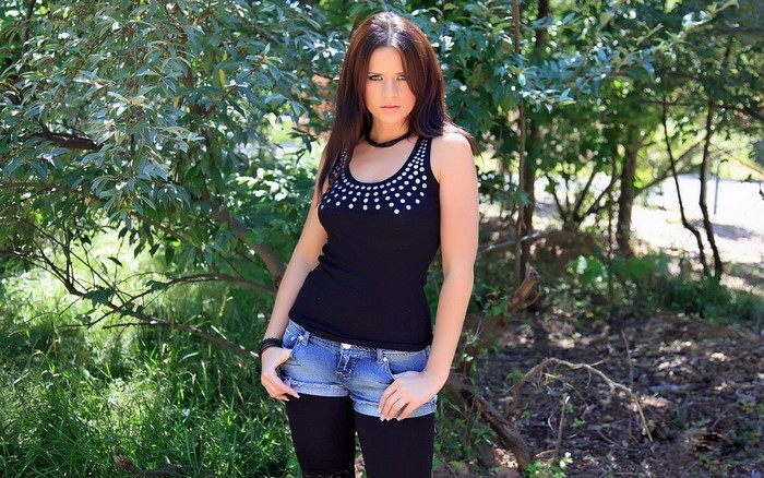 Woman in black top and denim shorts in forest