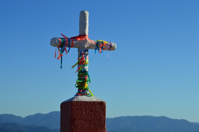 Cross decorated with colorful ribbons against a blue sky