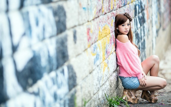 Asian woman posing against a graffiti wall