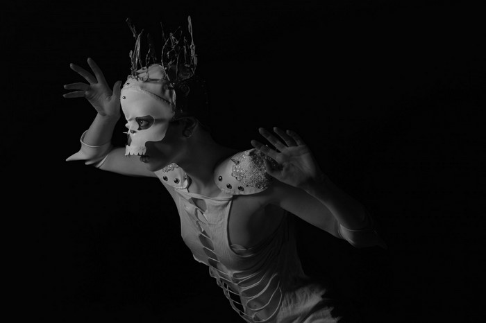 Woman in skull mask and ripped costume performing