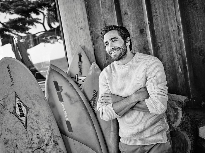 Jake Gyllenhaal leaning against surfboards