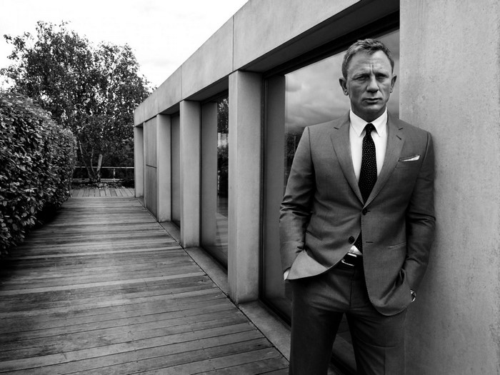 Daniel Craig in a suit standing on a wooden deck