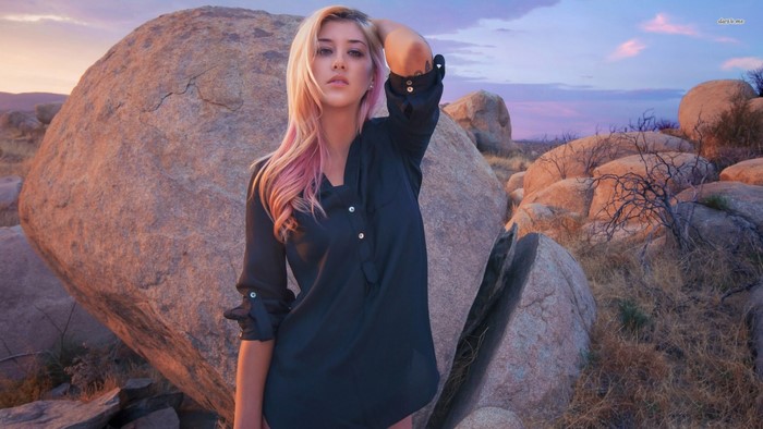 Woman posing in a rocky desert landscape at sunset