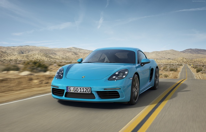 Blue Porsche 718 Cayman S driving on desert road