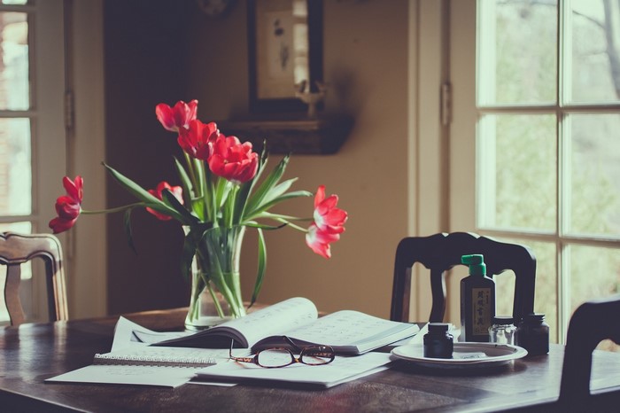 Red tulips on a table with books and ink bottles