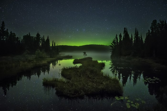Night sky over a misty lake with Aurora Borealis