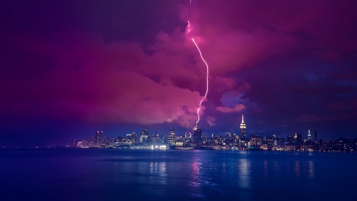 New York City skyline during a lightning storm over the water at night