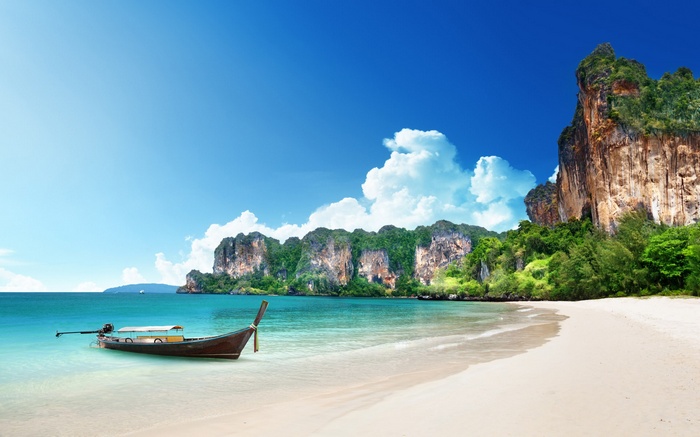 Longtail boat on a tropical beach with limestone cliffs