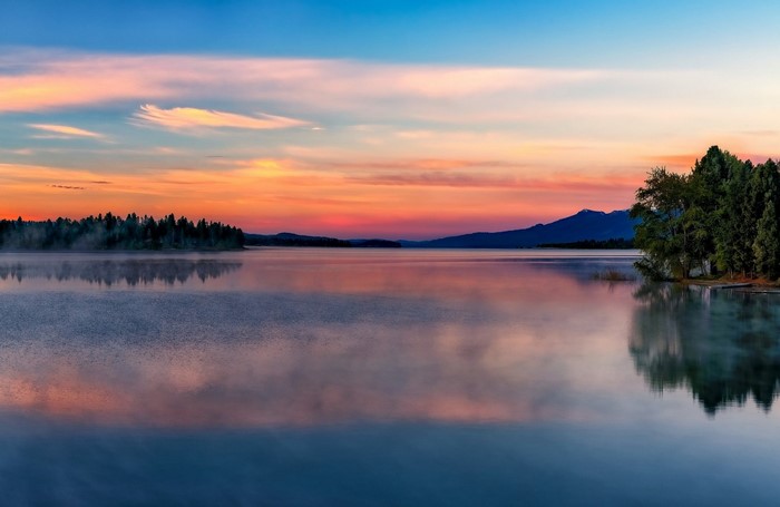 Lake at sunset with mountains and trees