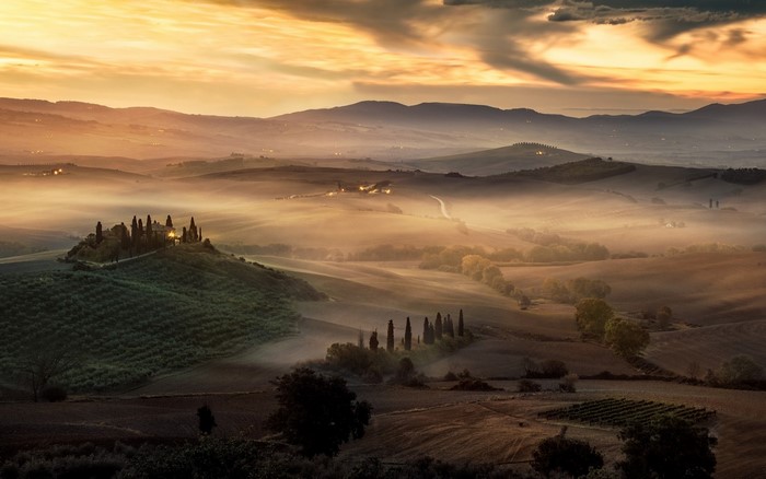 Tuscan landscape with rolling hills and mist at sunrise
