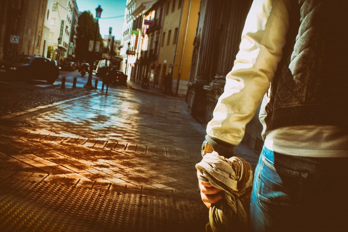 Person walking down a sunlit street in a city