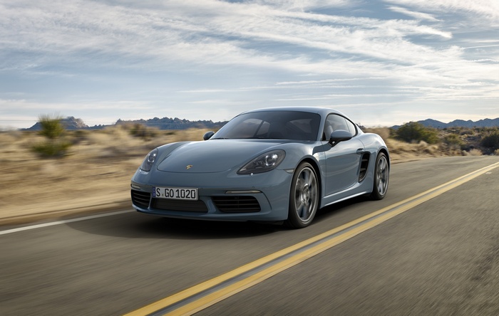 Grey Porsche 718 Cayman driving on a desert road