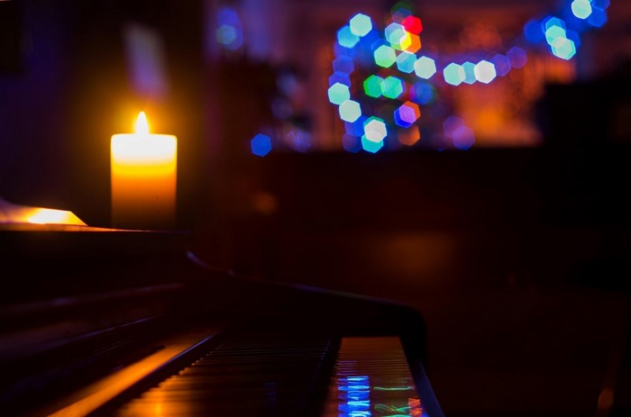 Candle and piano with Christmas lights bokeh