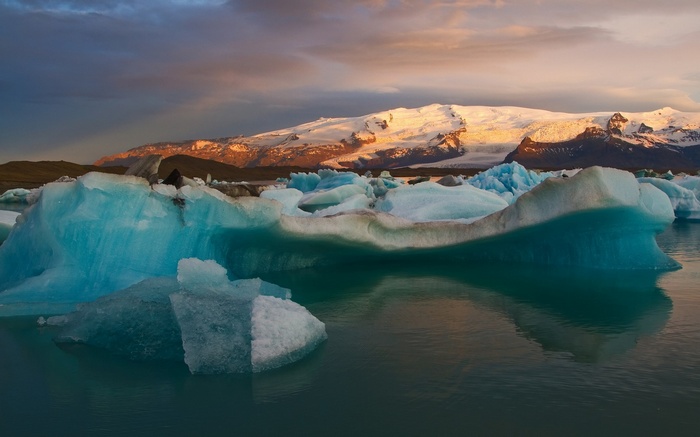 Icebergs floating in glacial lagoon with snow-capped mountains