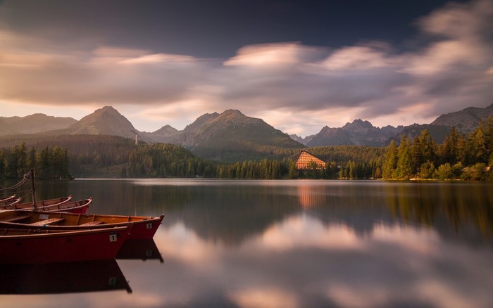 Boats on a lake with mountains and hotel at sunset