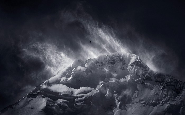 Monochrome mountain peak with birds flying in windy clouds