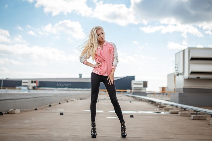 Woman in pink jacket and black leggings on rooftop
