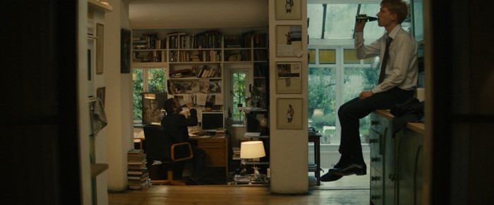Two men in a room with bookshelves and a window