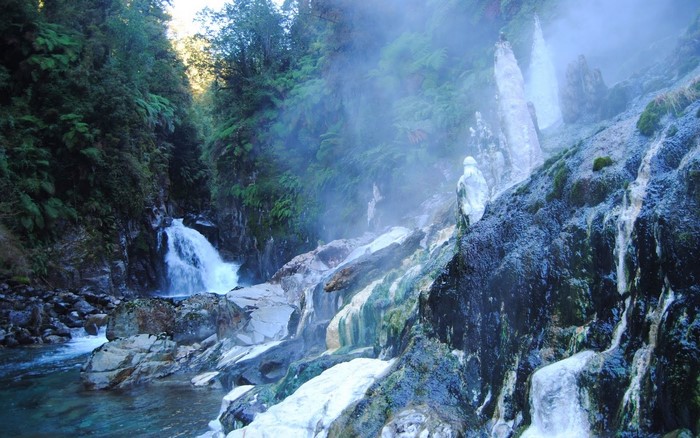 Waterfall and steaming rocks in a misty forest