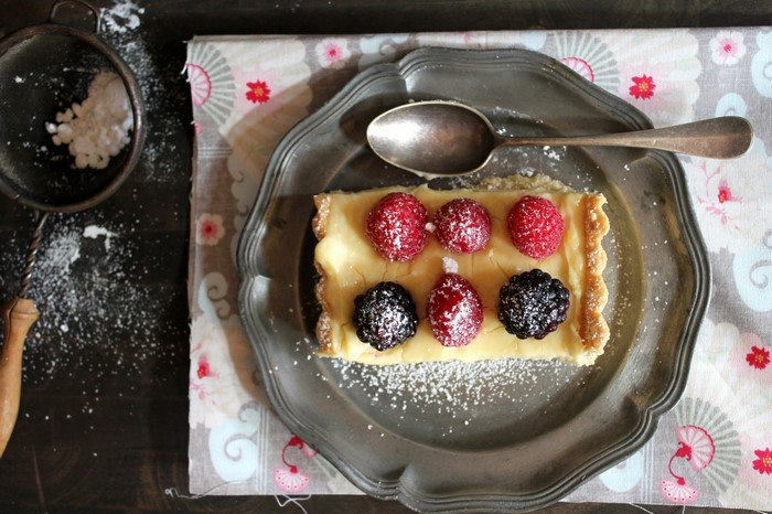 Rectangular tart with berries and powdered sugar on a plate