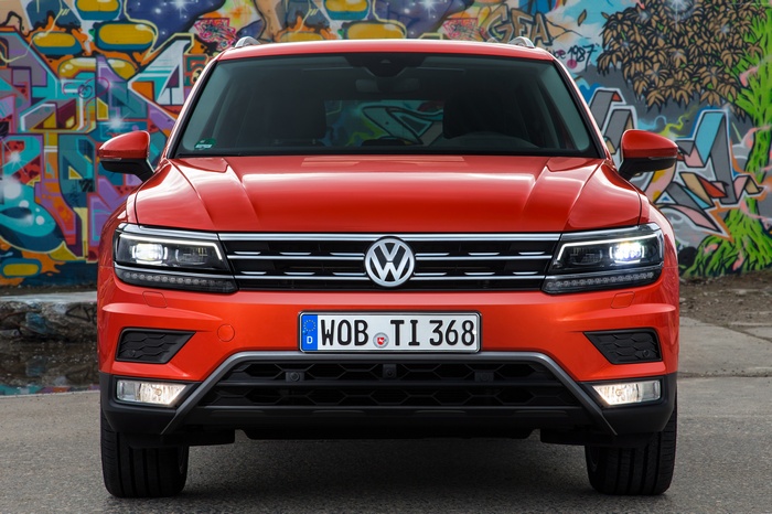 Orange Volkswagen Tiguan parked in front of graffiti wall