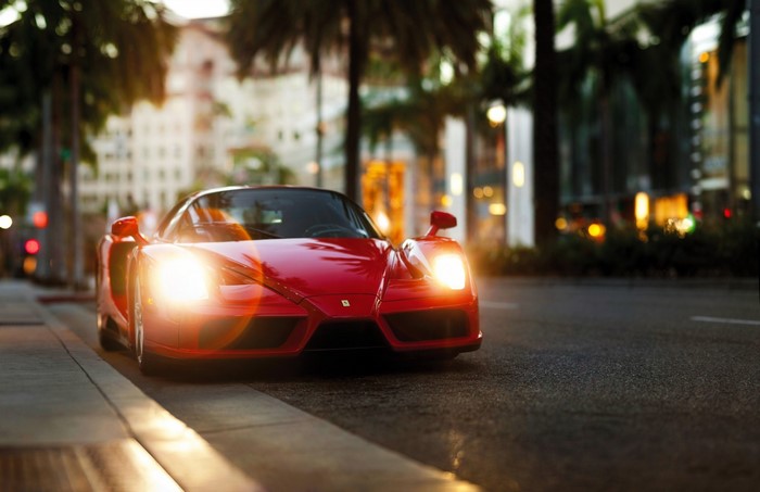Red Ferrari Enzo supercar parked on a street at dusk