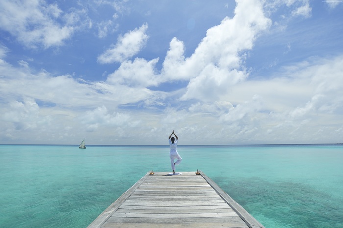 Person doing yoga on a pier in the ocean