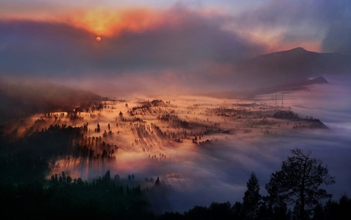 Misty valley at sunrise with sunbeams