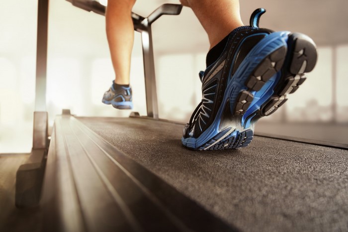 Person running on a treadmill wearing blue and black sneakers