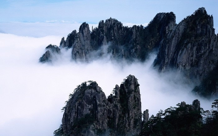Misty mountain peaks with sparse trees