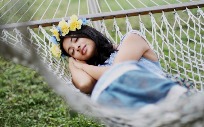 Woman wearing a flower crown sleeping in a hammock
