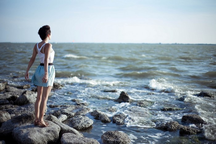 Woman standing on rocks by the sea