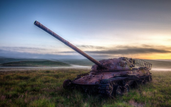 Abandoned tank in a misty field at sunrise