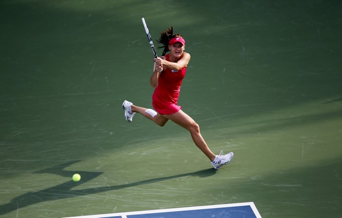 Agnieszka Radwańska playing tennis on a green court